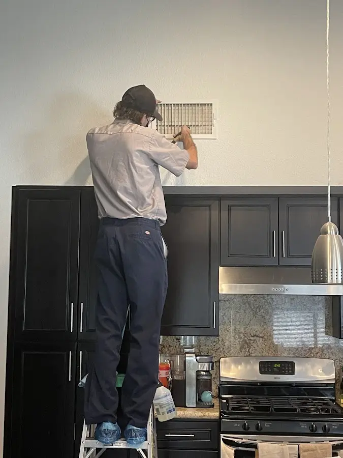 Technician inspecting an air vent during HVAC service in University City